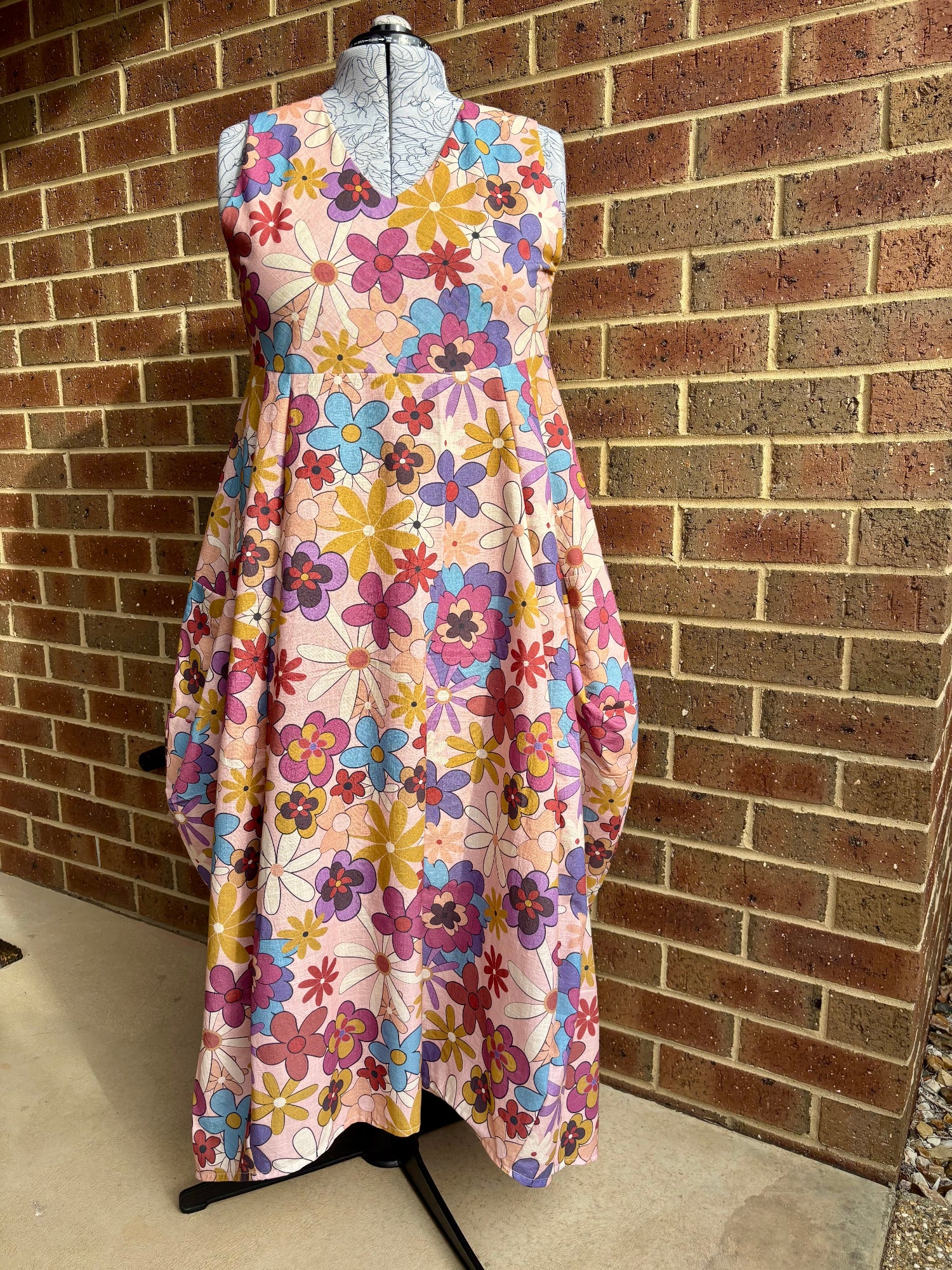 Colorful floral dress on a mannequin against a brick wall.