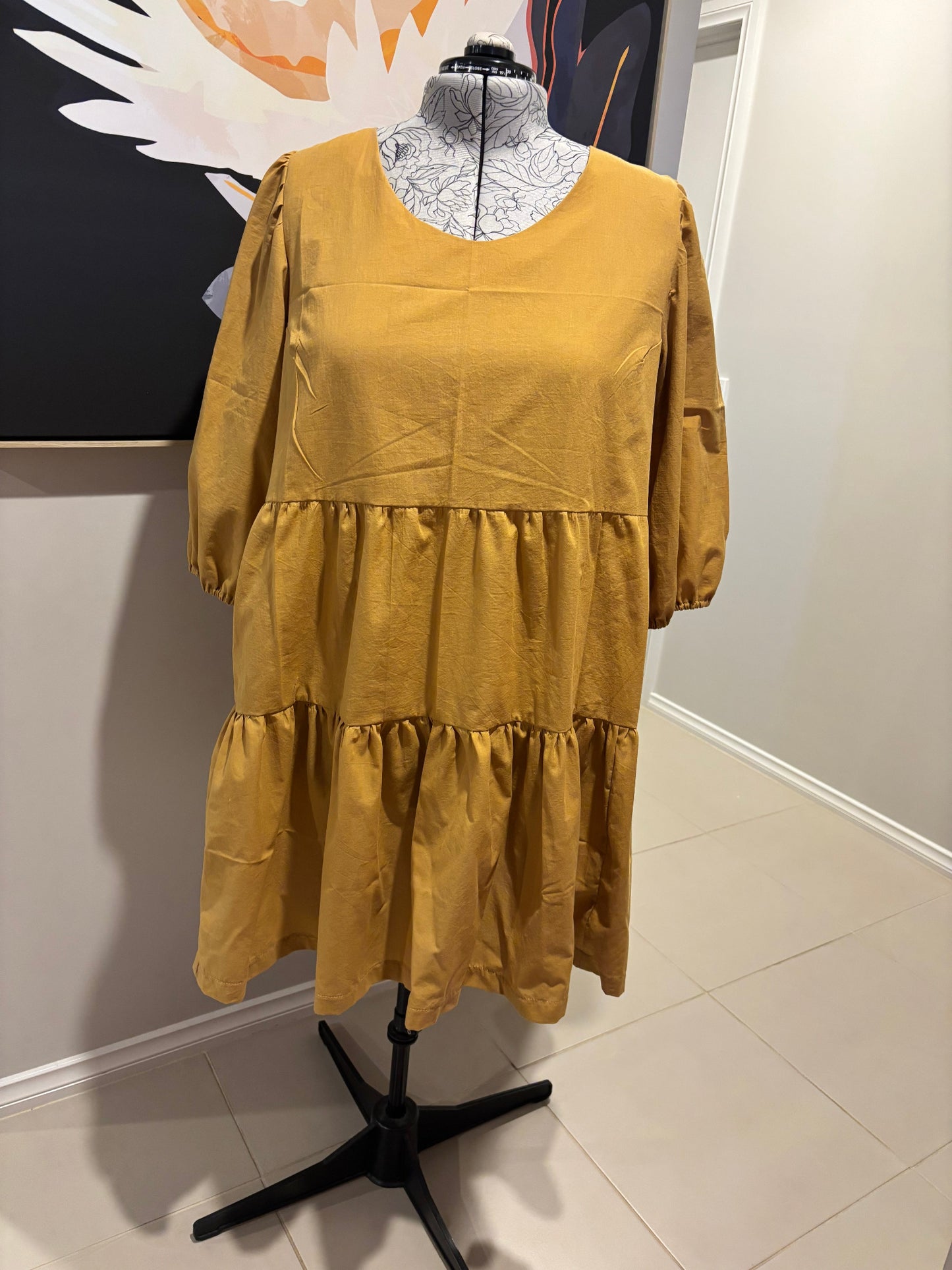 Gold dress on a mannequin against a white wall.