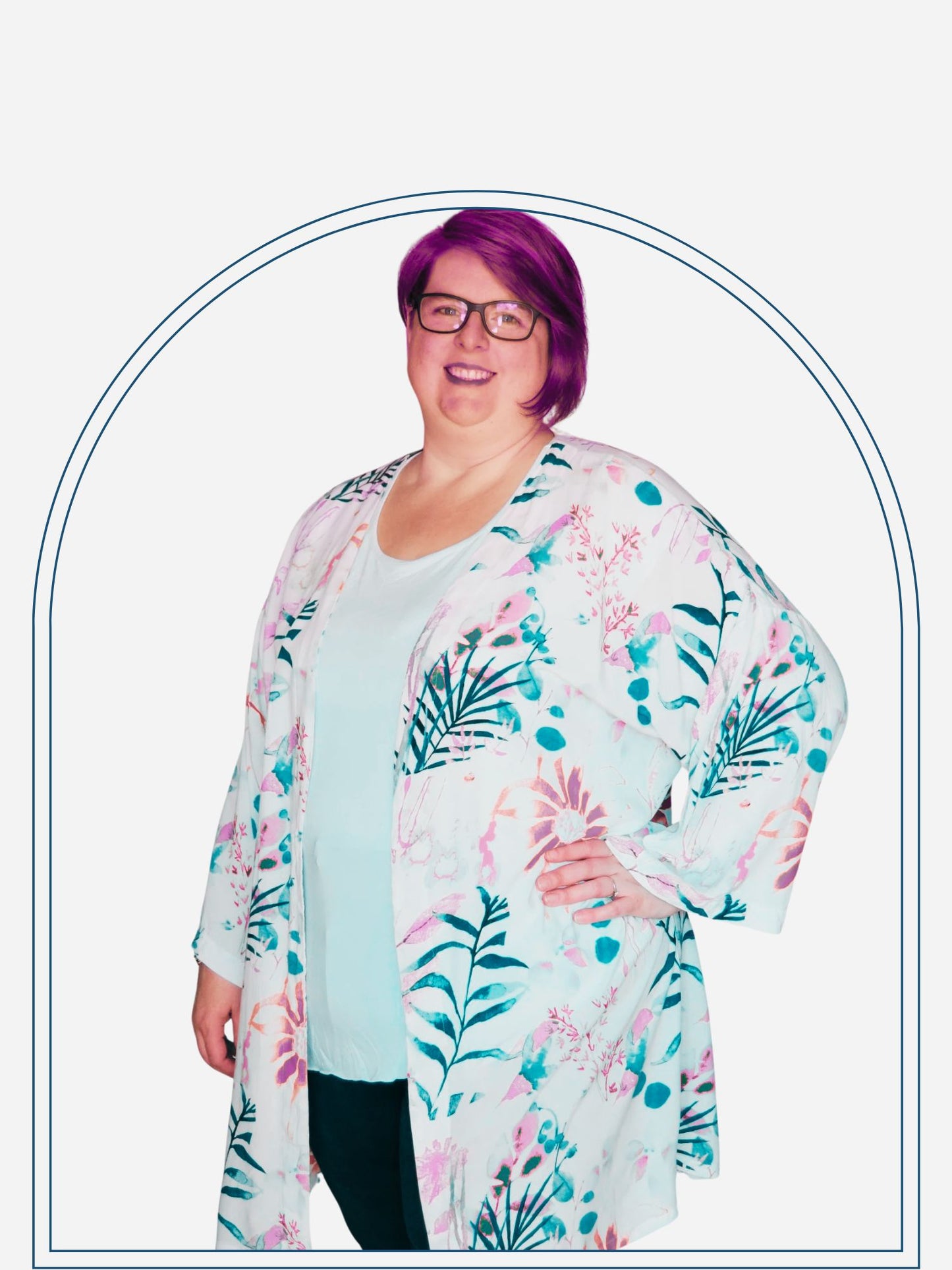 A woman modeling a colorful floral summer jacket, posing in a standing pose with one hand on her hip.