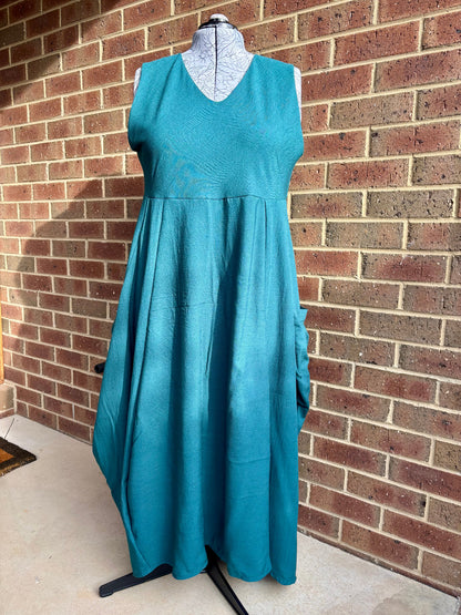 Teal dress on a mannequin against a brick wall.